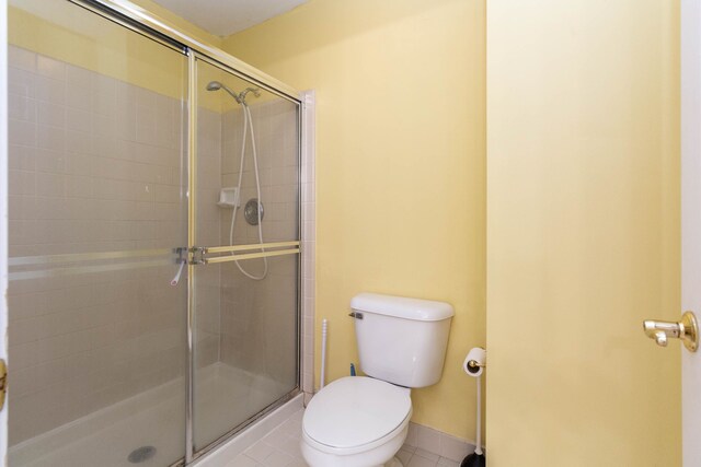 bathroom featuring a tile shower, tile patterned flooring, and toilet