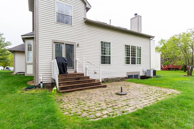 rear view of property with entry steps, a patio, central AC, and a lawn