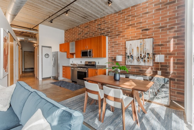 dining space featuring brick wall and track lighting