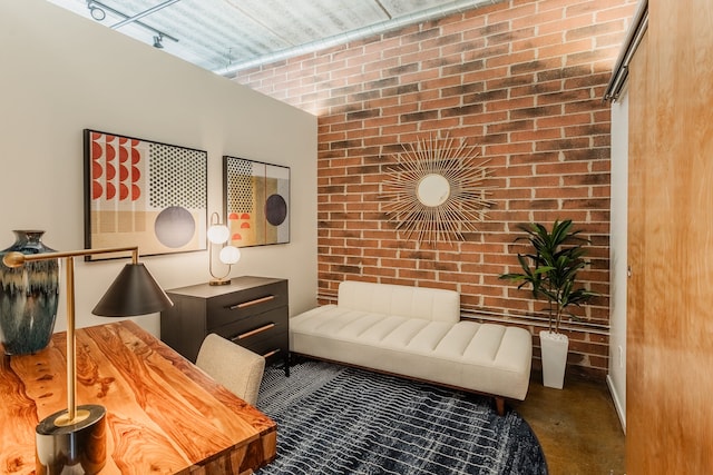 sitting room featuring brick wall and concrete floors