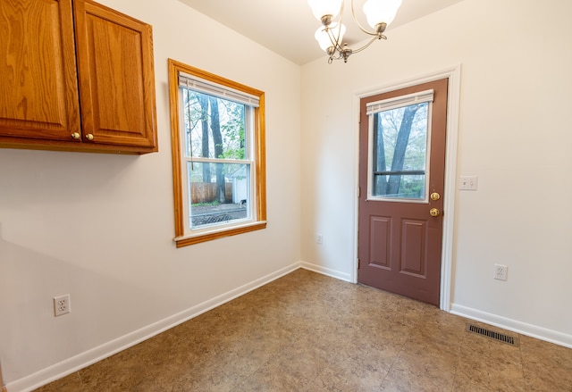 entryway with baseboards, a healthy amount of sunlight, an inviting chandelier, and visible vents