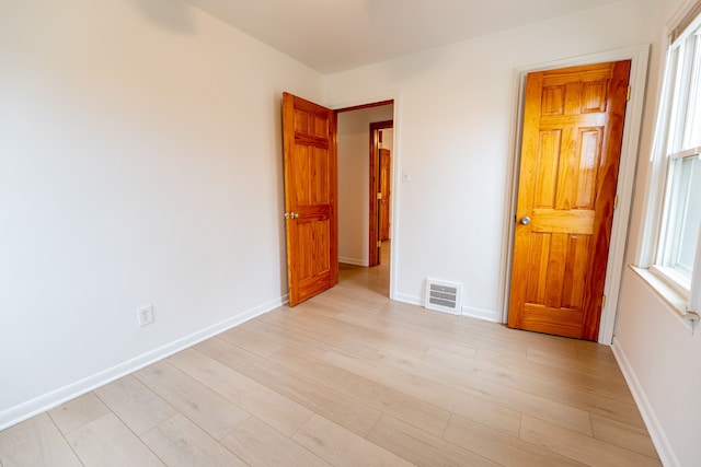 unfurnished room with baseboards, light wood finished floors, and visible vents