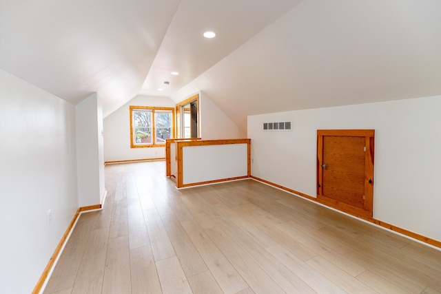 bonus room with vaulted ceiling, light wood finished floors, baseboards, and visible vents