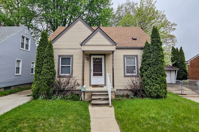 bungalow-style house with roof with shingles, fence, and a front yard