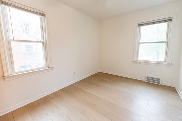 spare room with light wood-style flooring, baseboards, and visible vents