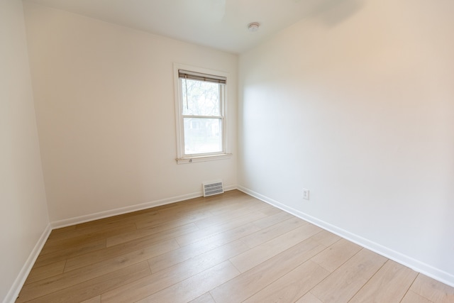 spare room featuring light wood-type flooring, visible vents, and baseboards