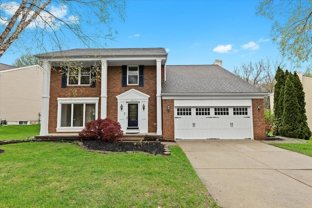 greek revival house with brick siding, a garage, a front lawn, driveway, and a chimney
