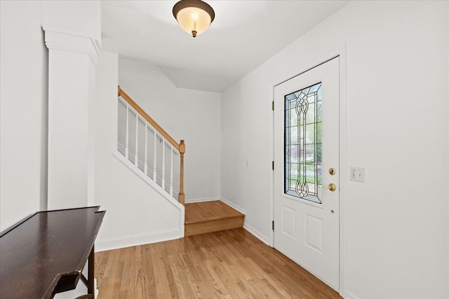 foyer entrance with light wood finished floors, stairs, and baseboards