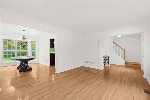 unfurnished living room featuring a chandelier, light wood-style flooring, stairs, crown molding, and baseboards