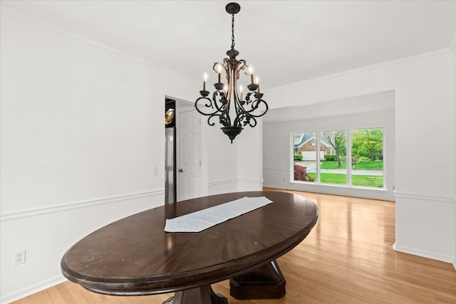 dining room with a chandelier, crown molding, light wood-type flooring, and baseboards