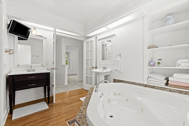 bathroom featuring wood finished floors, a jetted tub, and crown molding