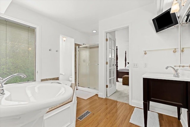 ensuite bathroom with wood finished floors, a stall shower, vanity, and a garden tub