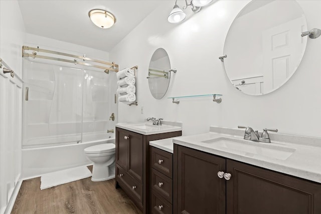 full bathroom with wood finished floors,  shower combination, toilet, and two vanities