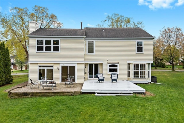 rear view of house with a chimney, a deck, a yard, central AC, and roof with shingles