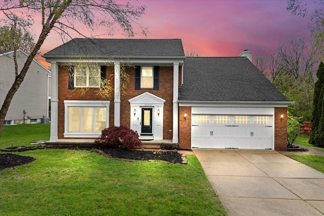 view of front of house with brick siding, driveway, an attached garage, a chimney, and a yard