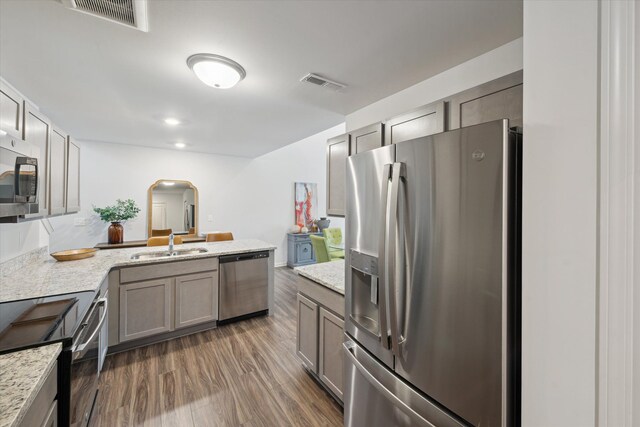 kitchen with stainless steel appliances, arched walkways, a peninsula, a sink, and dark wood-style floors