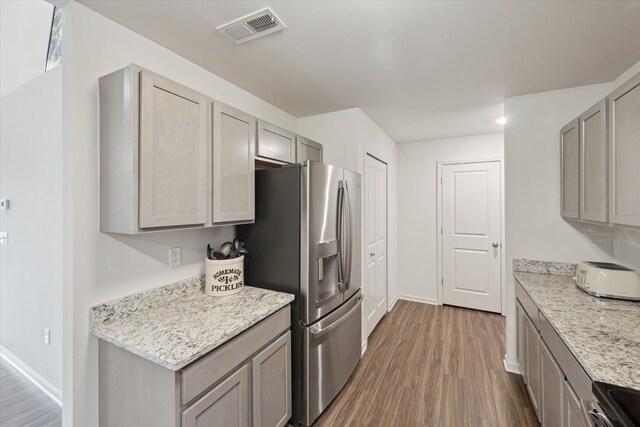 kitchen featuring dark wood-type flooring, gray cabinets, baseboards, stainless steel appliances, and light stone counters