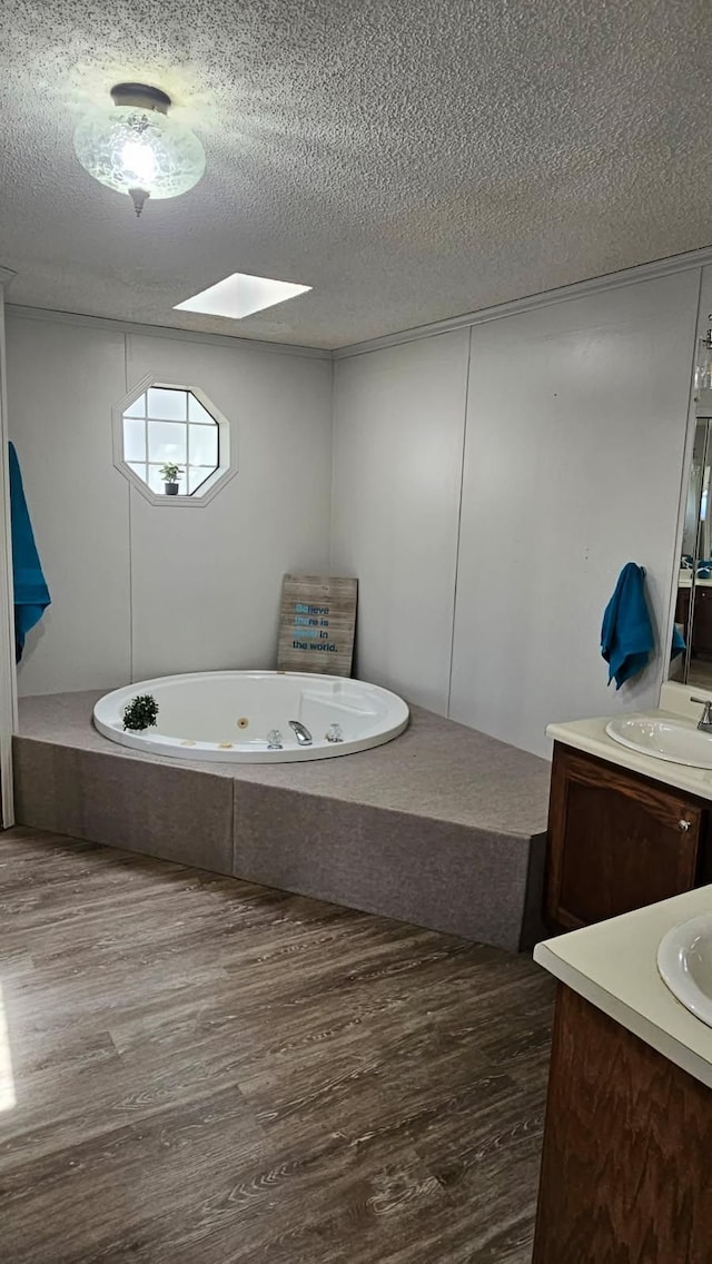 bathroom featuring wood finished floors, a textured ceiling, vanity, and a whirlpool tub
