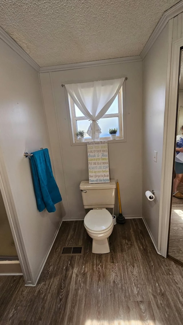 bathroom featuring ornamental molding, wood finished floors, toilet, and a textured ceiling