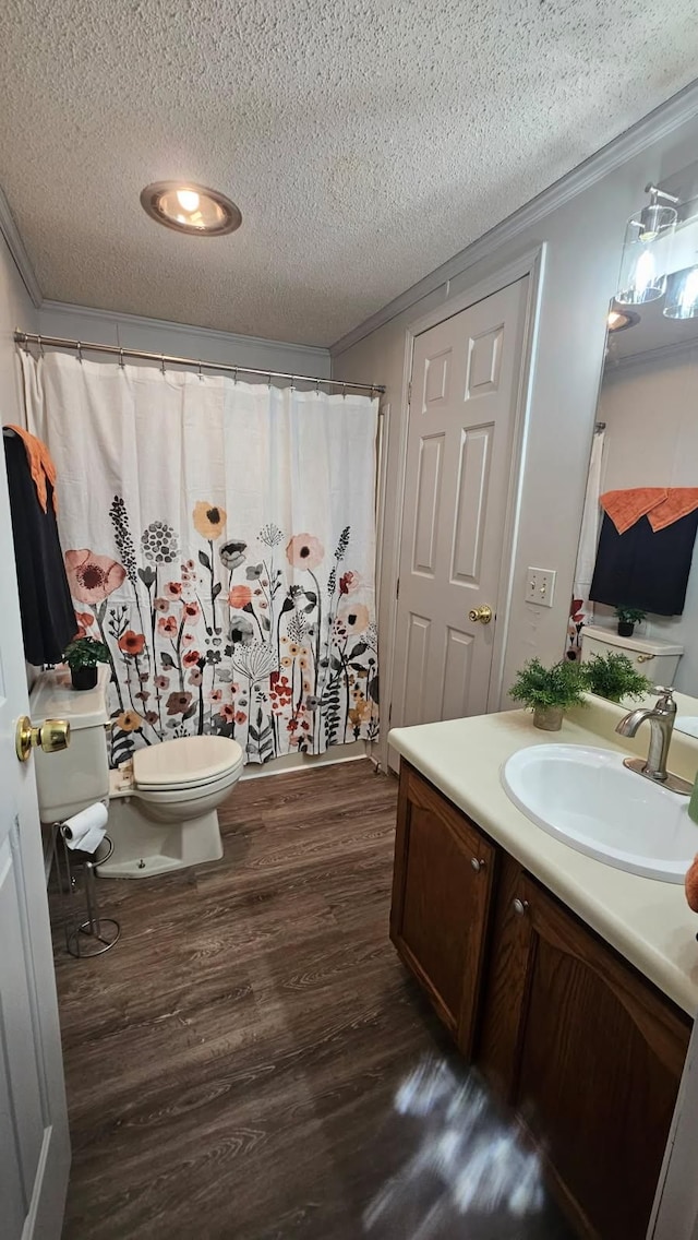 bathroom featuring a textured ceiling, wood finished floors, vanity, crown molding, and toilet