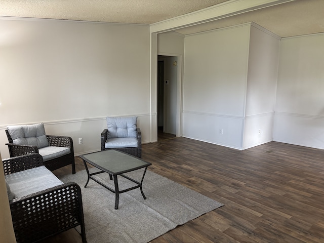 living area with wood finished floors, a textured ceiling, and crown molding