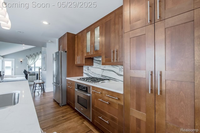 61 Cutting Dr, Troy, MI 48085 - kitchen with stainless steel appliances, brown cabinetry, glass insert cabinets, backsplash, and wood finished floors