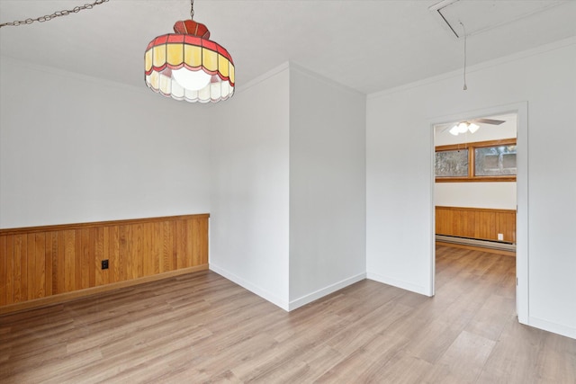 unfurnished dining area with a baseboard heating unit, ornamental molding, attic access, and wood finished floors