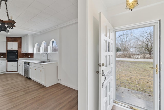 kitchen with a sink, oven, decorative backsplash, white cabinets, and stainless steel dishwasher