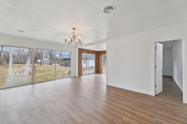 unfurnished dining area featuring baseboards, a chandelier, wood finished floors, and visible vents