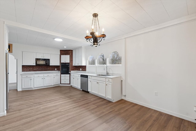 kitchen featuring a sink, white cabinetry, black appliances, light wood-style floors, and a chandelier