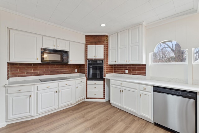 kitchen featuring crown molding, white cabinetry, and black appliances