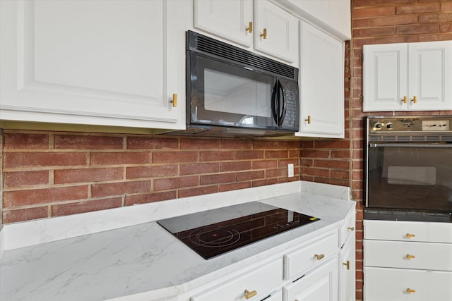 kitchen featuring white cabinetry, light stone counters, and black appliances