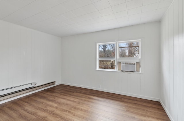 unfurnished room with a baseboard heating unit, cooling unit, and wood finished floors
