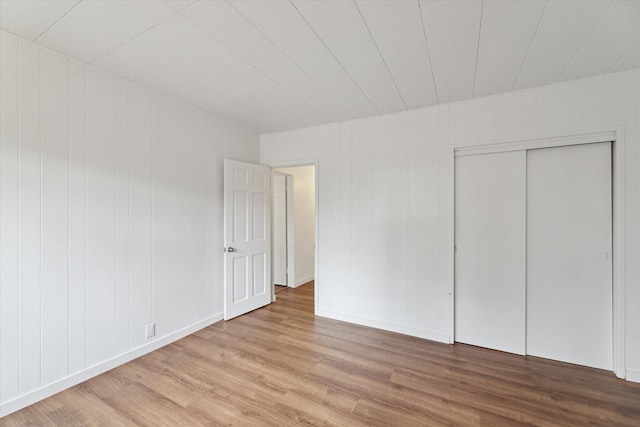 unfurnished bedroom with baseboards, a closet, and wood finished floors