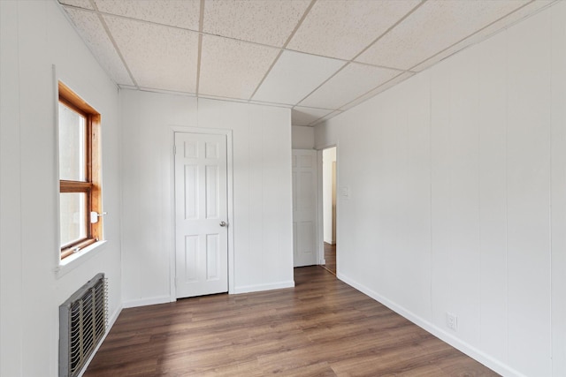unfurnished bedroom with visible vents, wood finished floors, baseboards, and a paneled ceiling