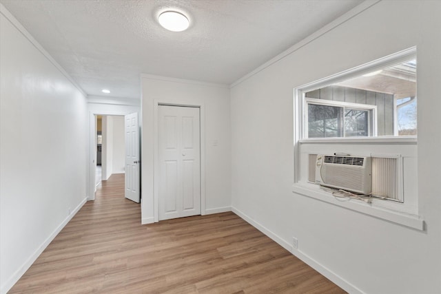 unfurnished room featuring crown molding, a textured ceiling, baseboards, and light wood-style floors