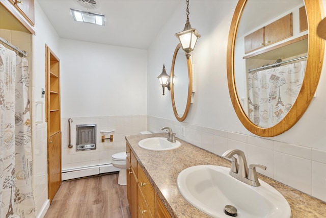 bathroom with a sink, toilet, wood finished floors, and a baseboard heating unit