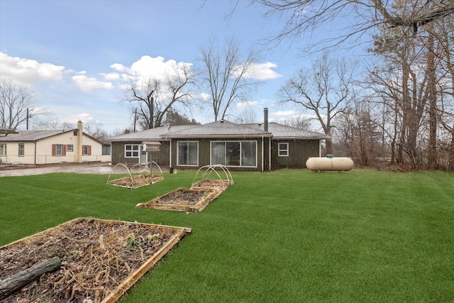back of property featuring a vegetable garden and a lawn