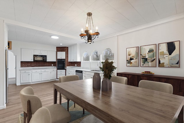 dining space with ornamental molding, light wood-style flooring, and a notable chandelier