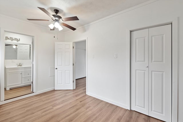 unfurnished bedroom featuring a closet, crown molding, light wood-style flooring, connected bathroom, and baseboards