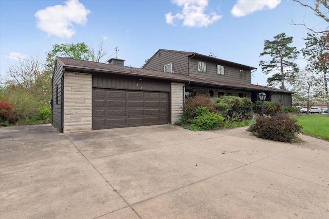 view of front of house with an attached garage, driveway, a chimney, and stone siding