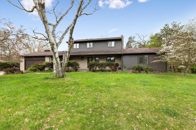 rear view of property featuring a yard and a garage