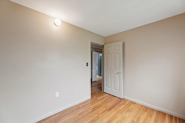 spare room with baseboards and light wood-type flooring