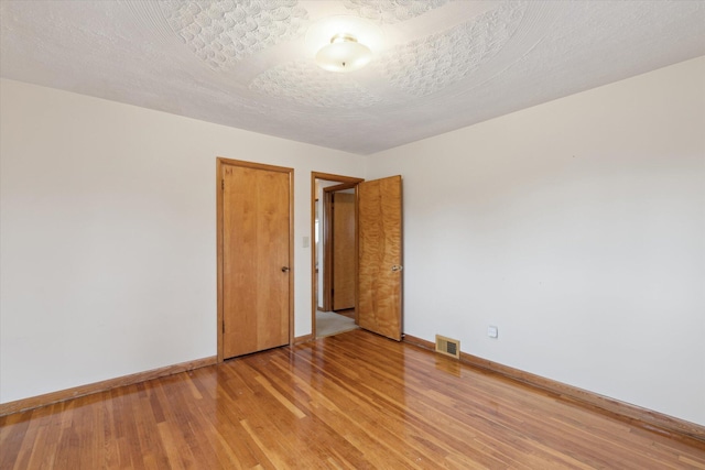 empty room with baseboards, light wood-style flooring, and visible vents