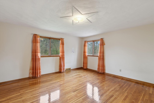 empty room with light wood-style flooring, baseboards, and visible vents