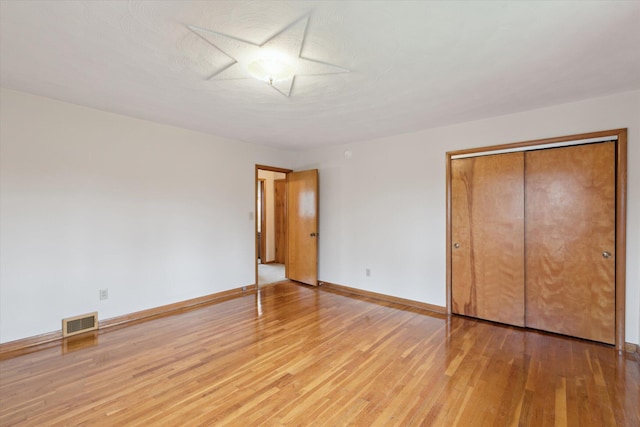 unfurnished bedroom with light wood finished floors, baseboards, a closet, and visible vents