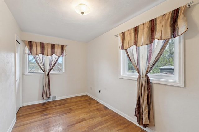 empty room with light wood-type flooring, visible vents, baseboards, and a healthy amount of sunlight