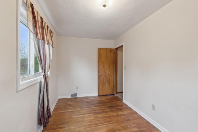empty room with baseboards, visible vents, and wood finished floors