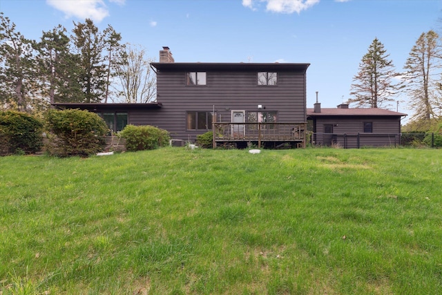 back of house featuring a chimney, a yard, a deck, and fence