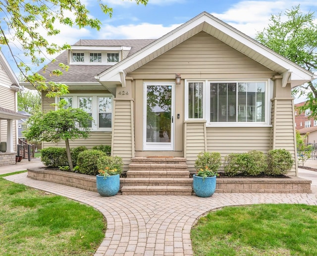 bungalow-style house with roof with shingles and entry steps